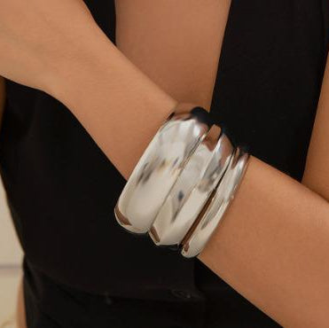 Silver bangles on a person's wrist with a blurred background