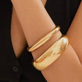 Gold bracelet on a person's wrist with a black background