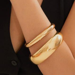 Gold bracelet on a person's wrist with a black background