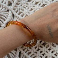 Hand wearing a brown bracelet on a textured white surface