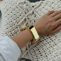 Gold bracelet on a wrist with a textured white fabric background