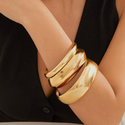 Gold bracelet on a person wearing a black sleeveless top.
