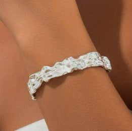 Silver ring with gemstones on a wrist against a neutral background