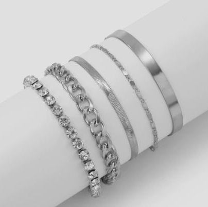 Set of silver bracelets on a white surface