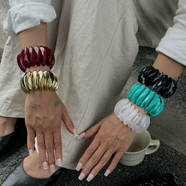 Person wearing colorful bangles on hands with a neutral background