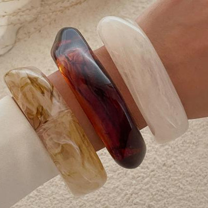 Three bangles in different colors on a textured surface