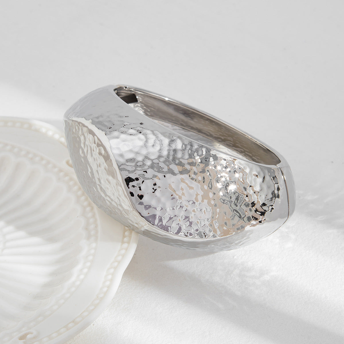 Silver ring with textured design on a white surface