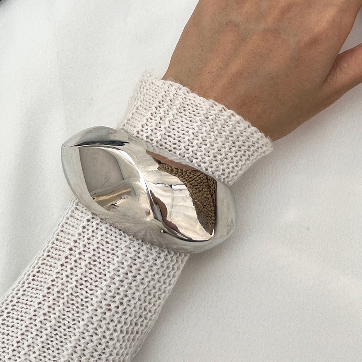 Silver ring on a white mesh wristband against a white background