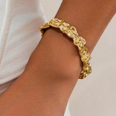 Gold chain bracelet on a wrist with a neutral background