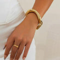Gold bracelet and ring on a hand against a white background