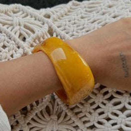 Yellow bracelet on a wrist with a textured white background