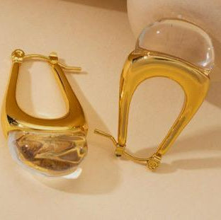 Gold hoop earrings with clear stones on a beige background