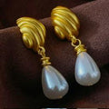 Gold earrings with pearl drops on a brown fabric background