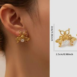 Gold earrings with pearl-like stones worn on an ear, shown with measurements and weight information.