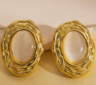 Pair of gold earrings with a beige stone on a beige background