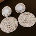 Decorative earrings with intricate designs on a dark background