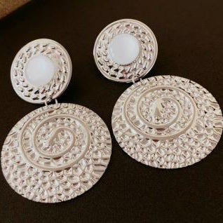 Decorative earrings with intricate designs on a dark background