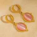 Gold hoop earrings with pink stones on a beige background