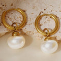 Gold hoop earrings with pearl drops on a textured stone surface