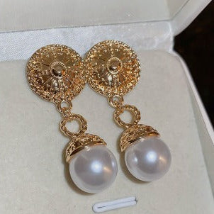 Gold earrings with pearl drops on a white background