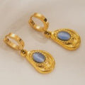 Gold earrings with blue stones on a beige background