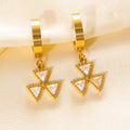Gold earrings with triangle-shaped charms on a beige fabric background