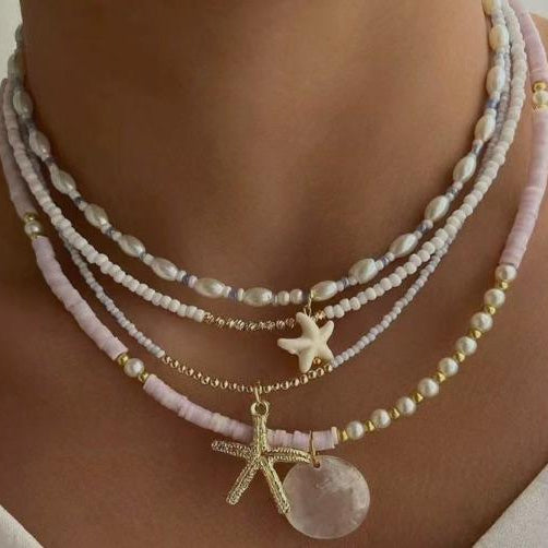 Necklace with starfish pendants and a large round pendant on a person's neck