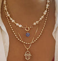 Two necklaces with pendants on a person's neck against a neutral background