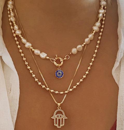 Two necklaces with pendants on a person's neck against a neutral background