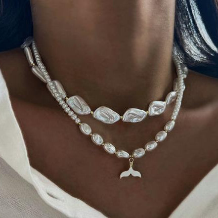 Pearl necklace with a mermaid tail pendant worn by a person.