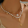 Gold and pearl necklace with starfish charms on a model against a neutral background