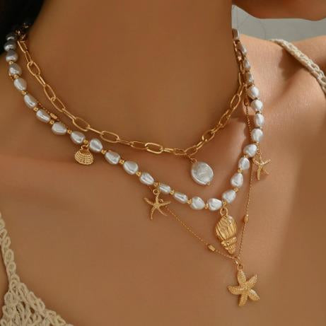 Gold and pearl necklace with starfish charms on a model against a neutral background