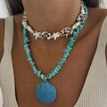Turquoise necklace with shell pendant worn by a person