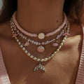 Necklace with various charms including a mermaid tail pendant on a person's neck.