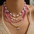 Necklace with pink beads and starfish charm on a model wearing a crochet top.