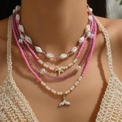Necklace with pink beads and starfish charm on a model wearing a crochet top.