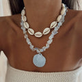 Necklace with shell and bead design on a person wearing a beige top.