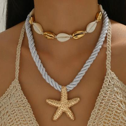 Necklace with starfish pendant and shell beads on a person wearing a crochet top.