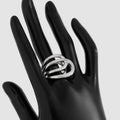 Silver ring on a black-gloved hand against a light gray background