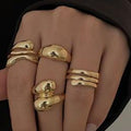 Gold rings on a person's fingers against a dark background