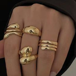 Gold rings on a person's fingers against a dark background