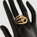 Gold ring on a black mannequin hand against a white background