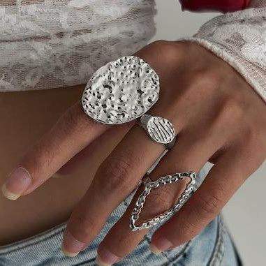Close-up of a hand wearing multiple silver rings with textured designs.