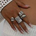 Hand wearing multiple silver rings on a textured white fabric background