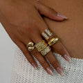 Hand wearing multiple gold rings with a neutral background