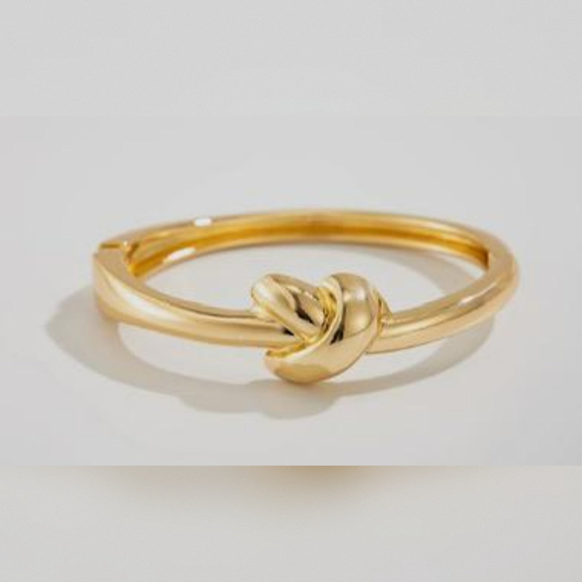 Gold knot ring on a light gray background