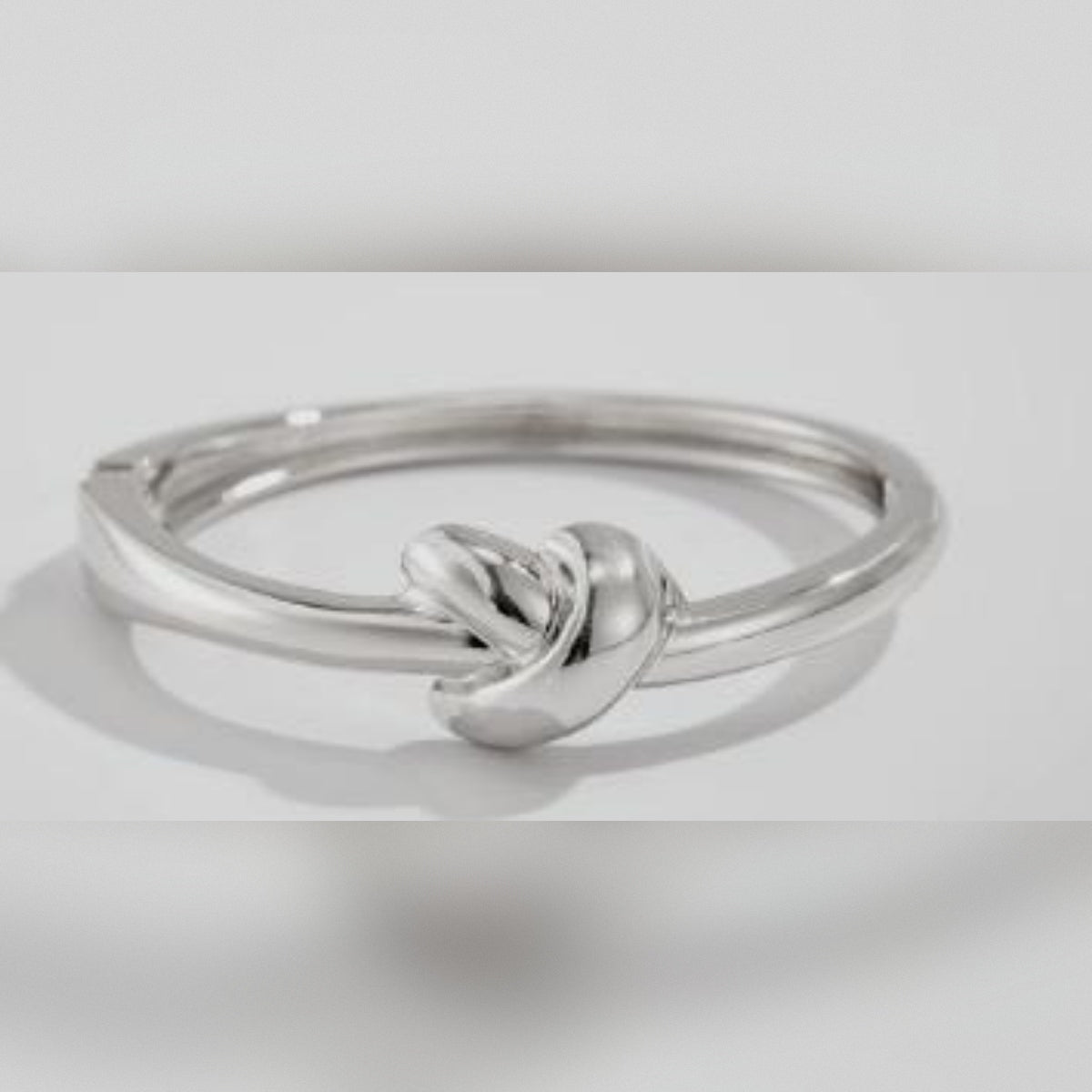 Silver ring with a knot design on a light gray background